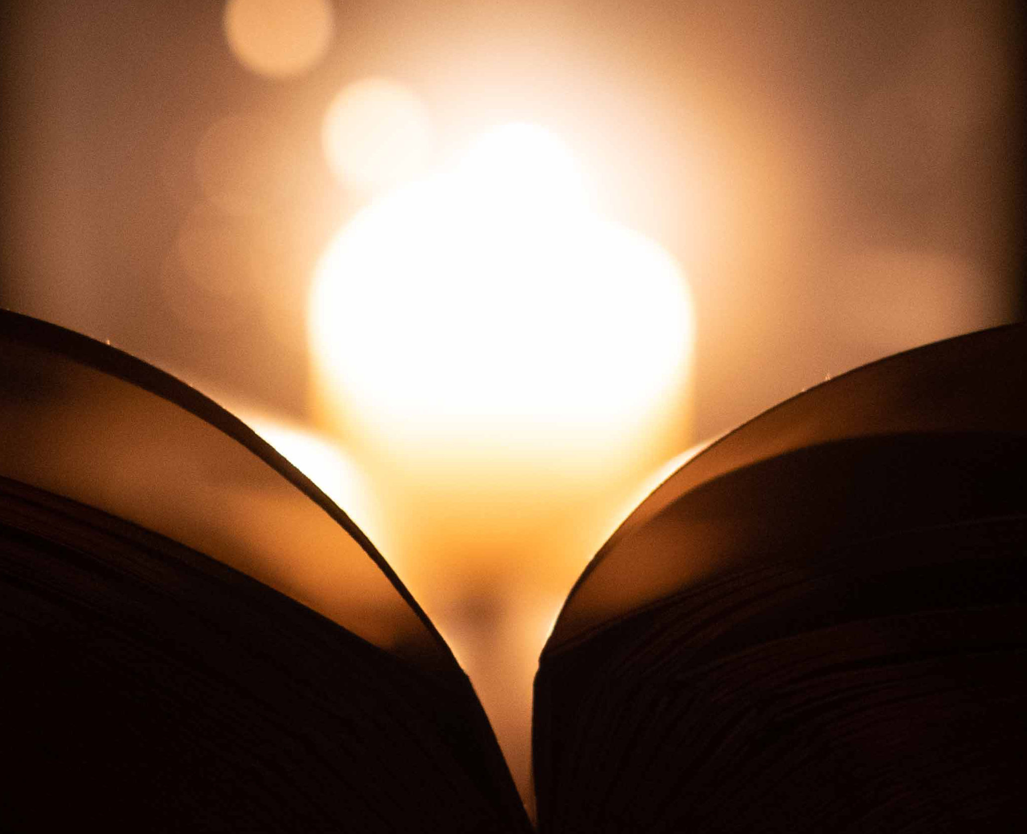 Von einer im Hintergrund befindlichen Kerze angestrahlte Buchseite